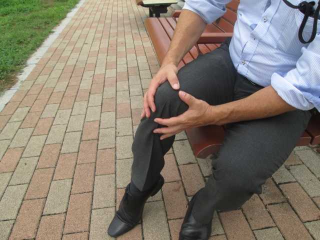 変形性膝関節症で膝を抑える男性